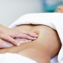 Hands massaging female abdomen.Therapist applying pressure on be Hands massaging female abdomen.Therapist applying pressure on belly. Woman receiving massage at spa salon